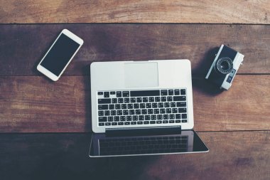 Ben dizüstü bilgisayar, akıllı telefon ve retro fotoğraf makinesi üstten görünüm üzerinde ahşap masa