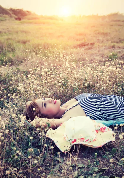 Young sexy woman lying in grass nearing her hat look into the sk — Stock Photo, Image