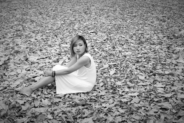 Jonge Aziatische vrouw helaas zit op droog blad in het bos alleen — Stockfoto