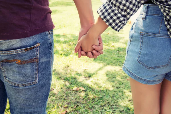 Pareja joven enamorada cogida de la mano caminando por el parque . —  Fotos de Stock