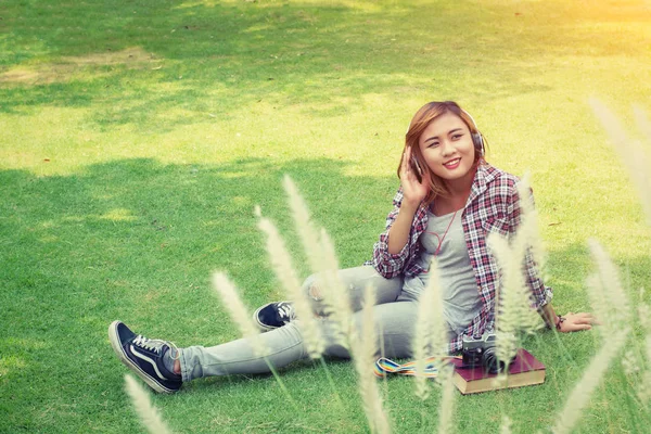 Joven mujer hipster sentada en el parque disfruta escuchando música wi —  Fotos de Stock