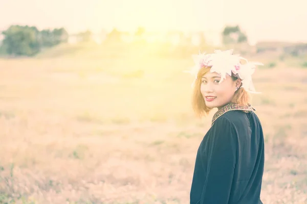 Mooie vrouw in het veld van de bloemen op zonsondergang. — Stockfoto