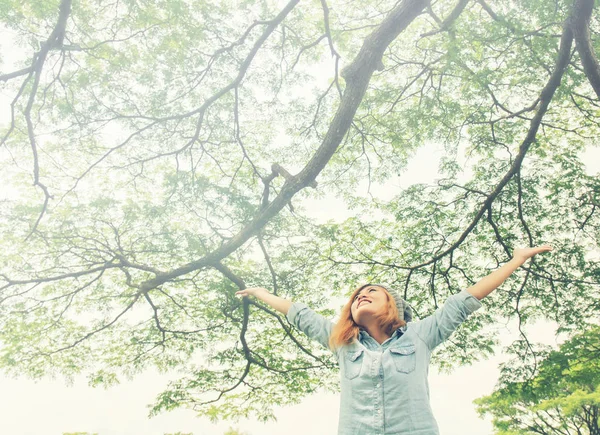 Mujer joven brazos abiertos de pie en la fresca vegetación de primavera con su — Foto de Stock