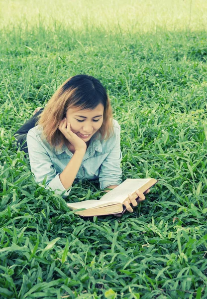 Leesboek voor jonge mooie hipster vrouw in het gras. — Stockfoto