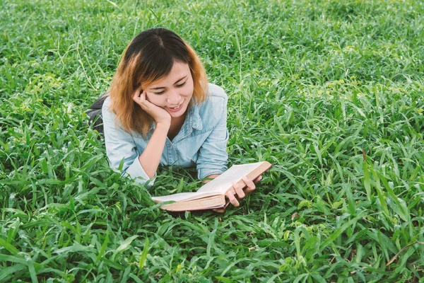 Junge schöne Hipster-Frau liest Buch im Gras. — Stockfoto