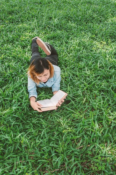 Молода красива хіпстерка читає книгу на траві . — стокове фото