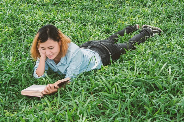Junge schöne Hipster-Frau liest Buch im Gras. — Stockfoto