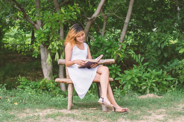 Bella donna sola seduta a leggere sulla panchina . — Foto Stock