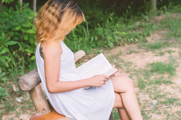 Hermosa mujer solitaria sentada leyendo en el banco . — Foto de Stock