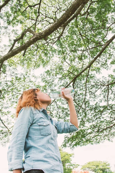 Leven van de vrouw: mooie jongedame drinkwater op groen park — Stockfoto