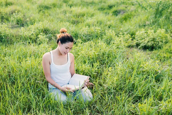 Jonge mooie Aziatische vrouw zitten en lezen van boek in de mead — Stockfoto