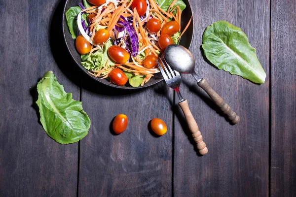 Salade fraîche avec tomates et légumes verts mélangés sur fond de bois — Photo