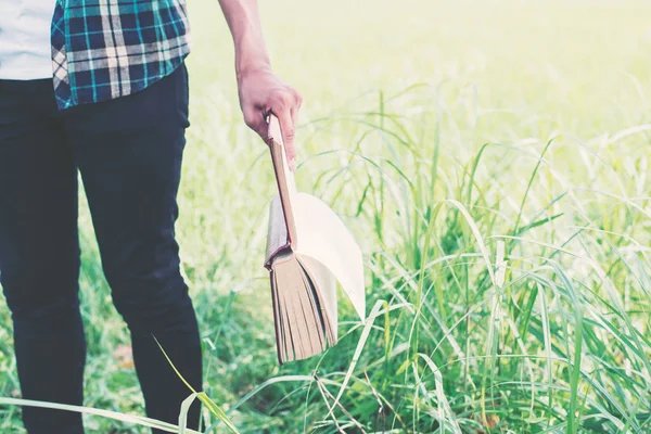 Mann hält Bücher in der Hand auf der grünen Wiese. — Stockfoto