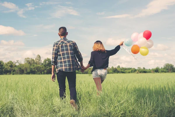 Back of happy young asian couple holding balloon and walk togeth — Stock Photo, Image
