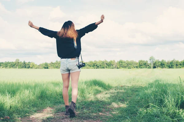 Costas de mulher jovem carregando câmera retro no campo de grama desfrutar de t — Fotografia de Stock