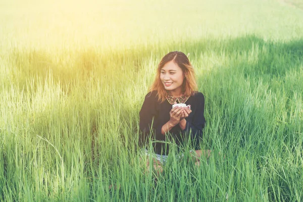Hipster młoda kobieta siedzi na zielonej trawie picia gorącej kawy — Zdjęcie stockowe