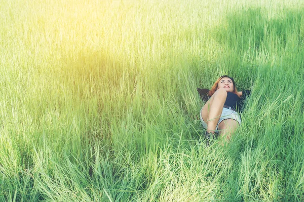 Schöne junge Frau im Liegen auf grünem Gras genießen das Leben und h — Stockfoto