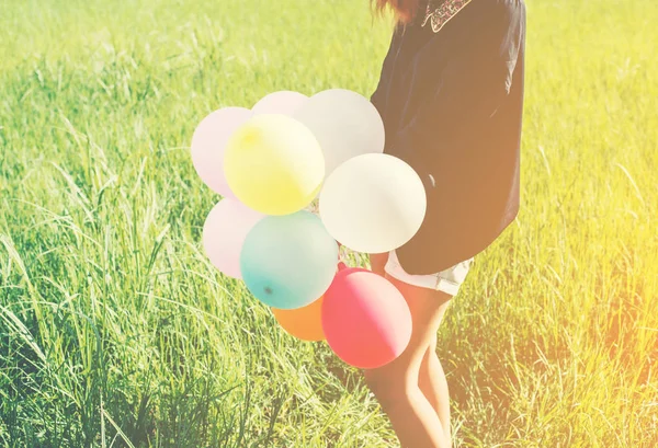 Happy young beautiful woman and colorful balloons in grassland. — Stock Photo, Image