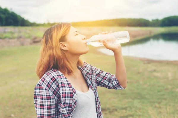 Jonge hipster vrouw drinkwater in zomer groen park. — Stockfoto