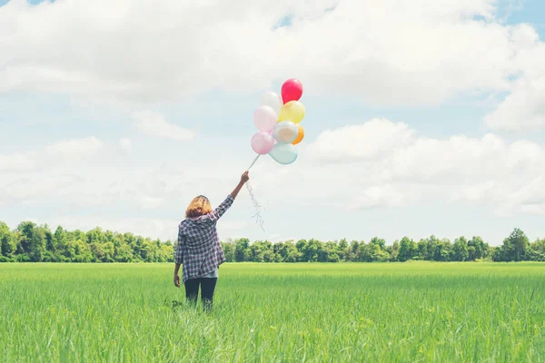 Costas de jovem hipster mulher asiática com balões coloridos na grama — Fotografia de Stock