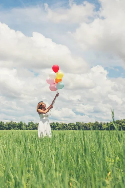 Feliz joven hermosa mujer sosteniendo globos en el campo de hierba — Foto de Stock