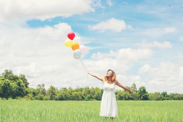 Joyeux jeune belle femme avec des ballons dans le champ d'herbe enj — Photo