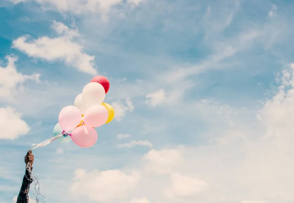 Glad ung hipster mannen håller färgglada ballonger i gräsmark e — Stockfoto