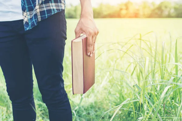 Manos de hombre sosteniendo libros en prado verde . — Foto de Stock