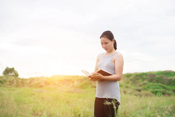 Молода жінка стоїть читати книгу на луках . — стокове фото