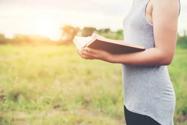 Giovane donna in piedi lettura libro a prati . — Foto Stock