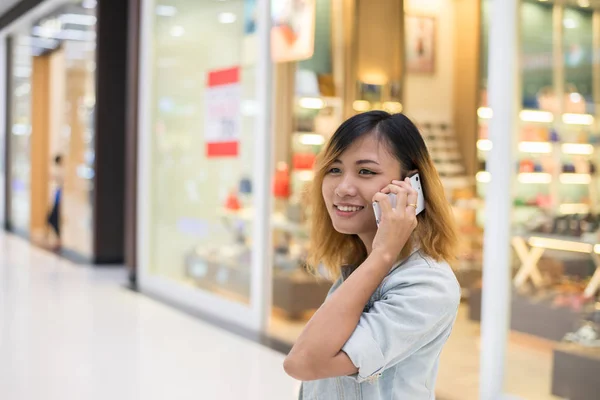 Ung vacker kvinna samtalen med en mobiltelefon i köpcentrum. — Stockfoto