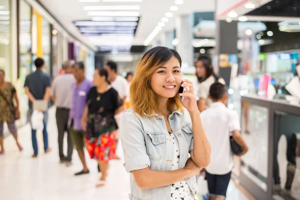 Ung vacker kvinna samtalen med en mobiltelefon i köpcentrum. — Stockfoto