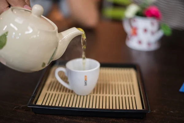 Verser le thé vert chaud à la tasse . — Photo