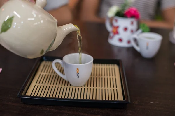 Pouring hot green tea to cup. — Stock Photo, Image