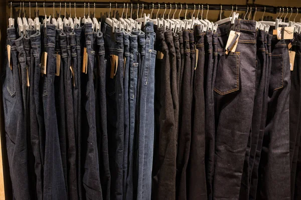 Jeans on clothes rail in clothing store at shopping mall.