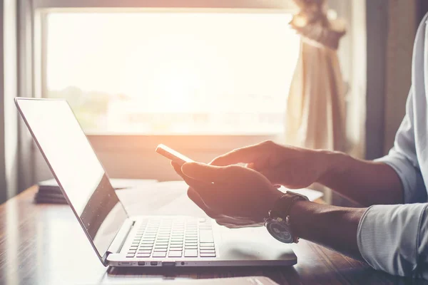 Ofis Masası, dizüstü bilgisayar ile cep telefonu kullanarak işadamı eller.