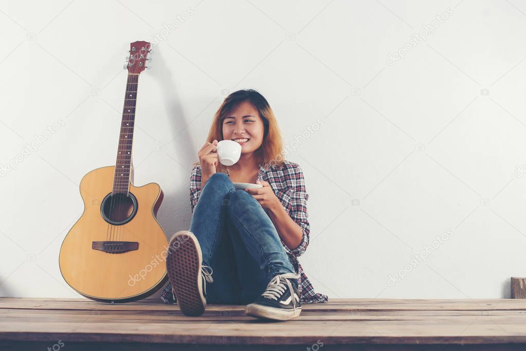 Young hipster woman  drinking coffee chillin' with guitar sittin