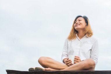 İçinde bankta oturmuş kahve tutan güzel kadın 
