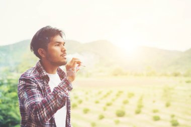 Hipster adam duman sigara, bir dağın duruyor. Arasında