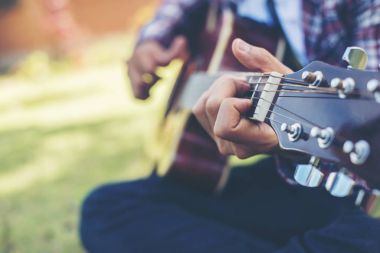 Genç hipster adam uygulanan gitar parkta mutlu yakın çekim