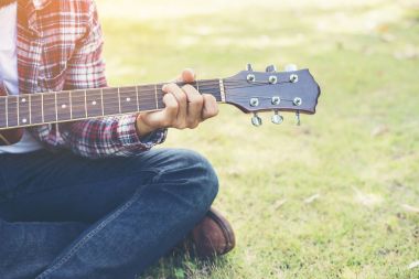 Genç hipster adam gitar parkta mutlu uygulanan ve p zevk