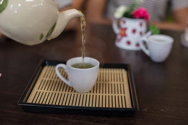 Verser le thé vert chaud à la tasse . — Photo