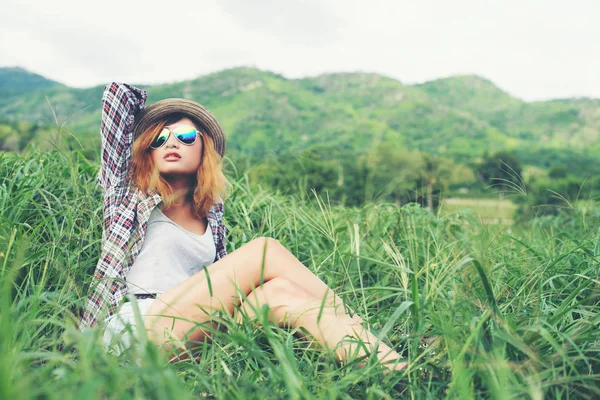 Mulher hipster bonita sentado em um prado com a natureza e moun — Fotografia de Stock