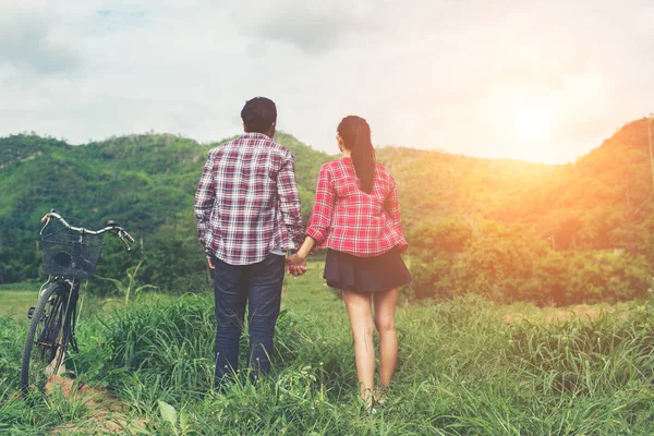 Young hipster couple holding hands walking on the meadow relaxin — Stock Photo, Image