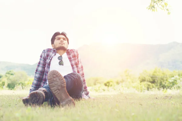 Νέοι hipster άνδρας κάθεται στο γρασίδι στο πάρκο, Απολαύστε με n — Φωτογραφία Αρχείου