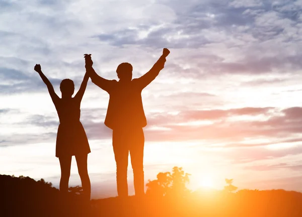 Silhouet van jong koppel samen armen omhoog in de lucht van happin — Stockfoto