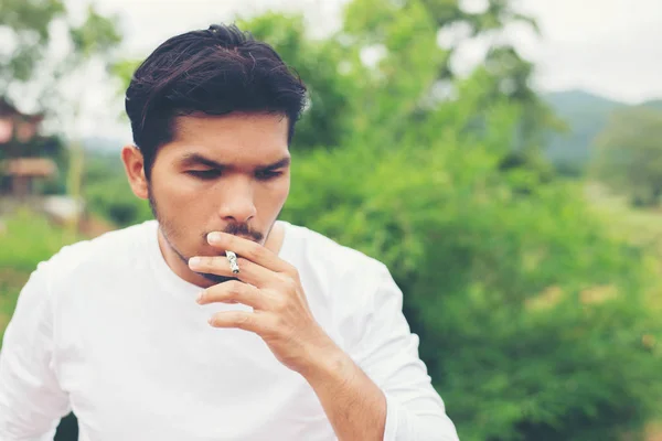 Joven hipster hombre tomando descanso, fumar cigarrillo con la naturaleza y — Foto de Stock