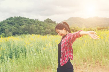 Eller yükselterek genç mutlu kadın sarı çiçek alanına sunset bulvarında
