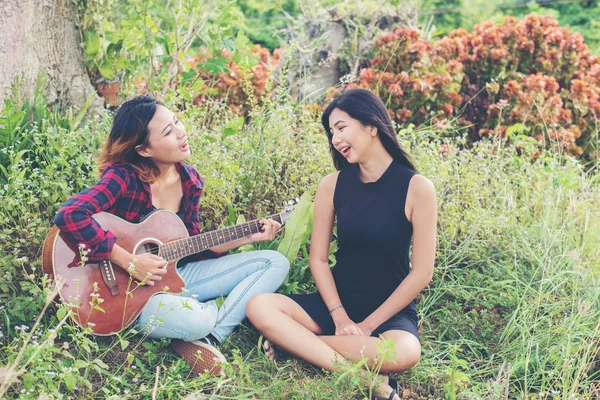 Ung tonårig tittar på hennes väninna medan du spelar gitarr, — Stockfoto