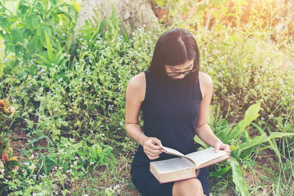 Rilassato giovane bella donna leggendo un libro sul prato con su — Foto Stock